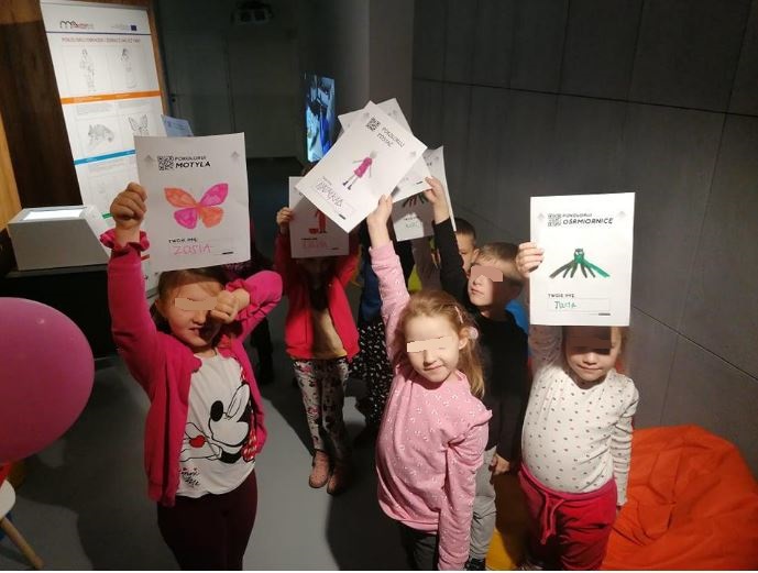The kids happily show their own drawings.